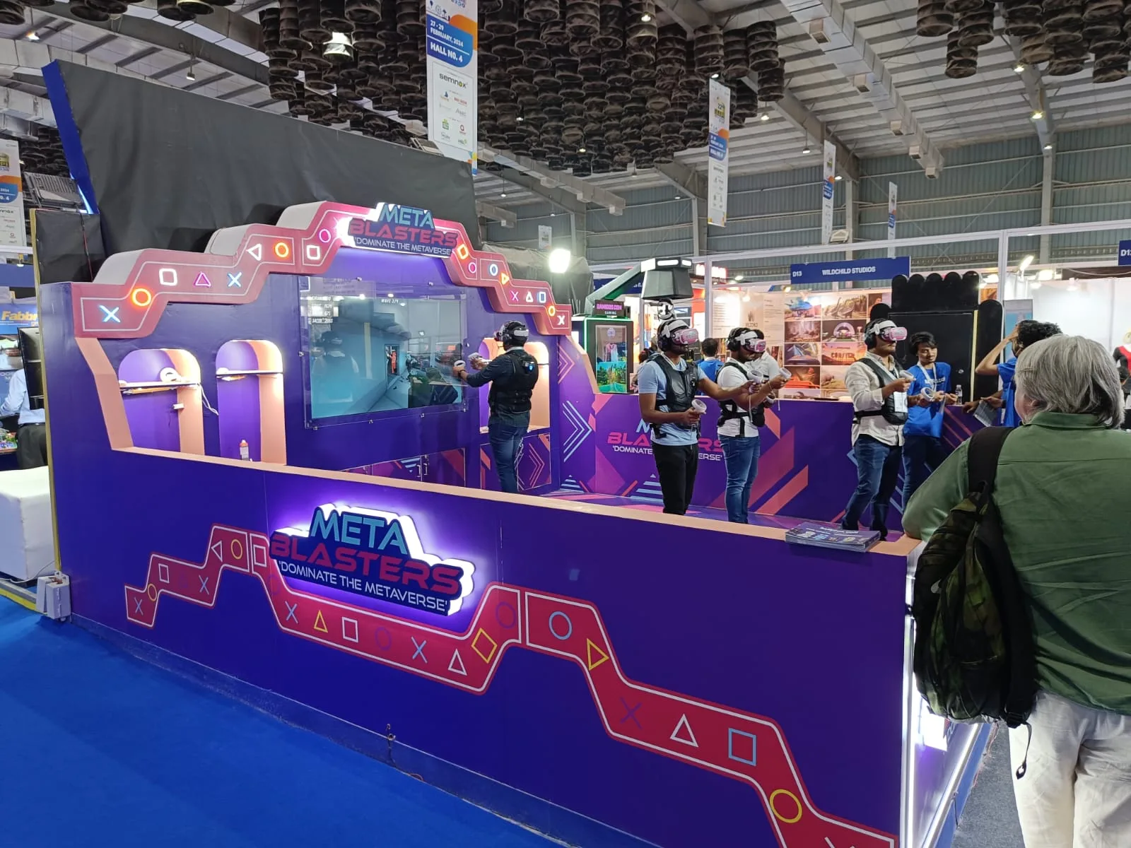Purple META BLASTERS stand with visitors and expo hall behind