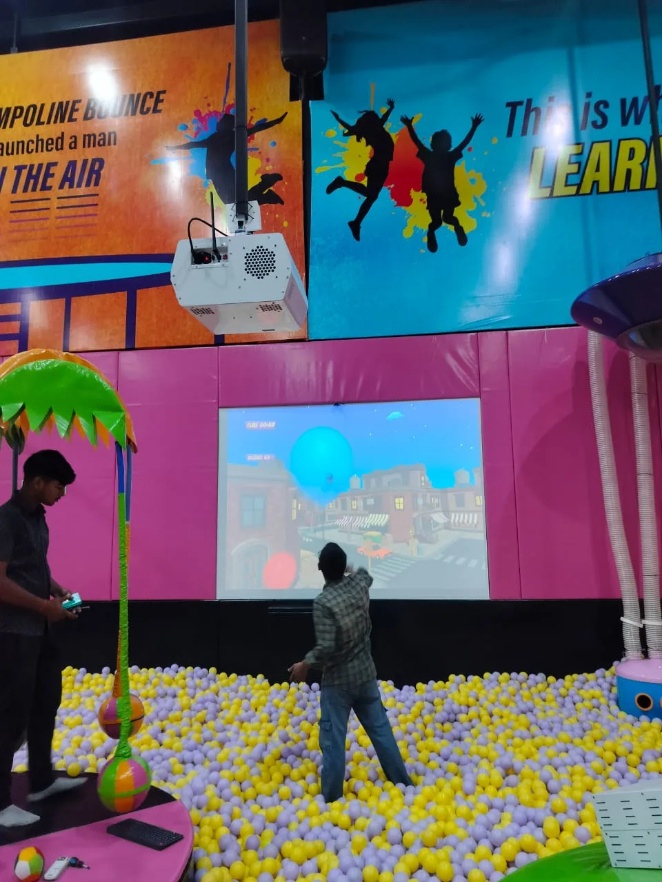 Man and child playing a wall projection game over a ball pit