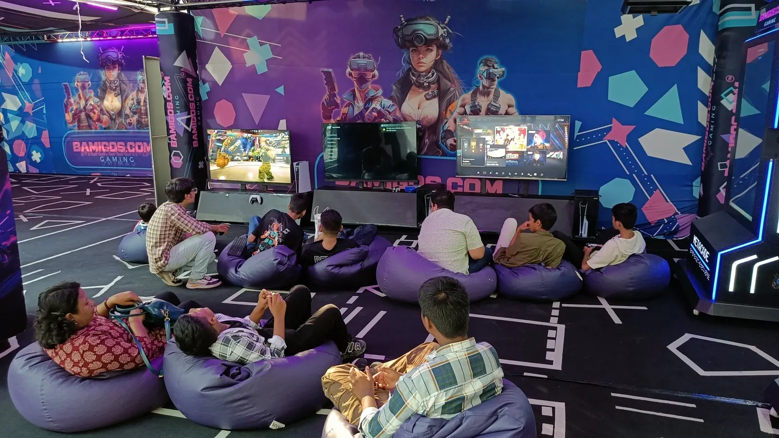 Visitors on bean bags watching game screens inside the Bamigos Gaming VR arena