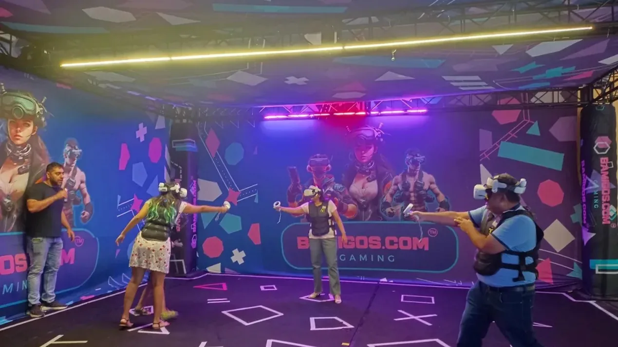 Players in headsets and vests playing a multiplayer VR game in front of the BAMIGOS.COM GAMING arena wall