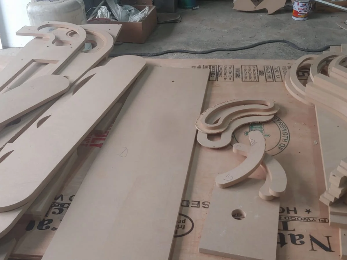 CNC-cut wooden cabinet parts laid out on a table