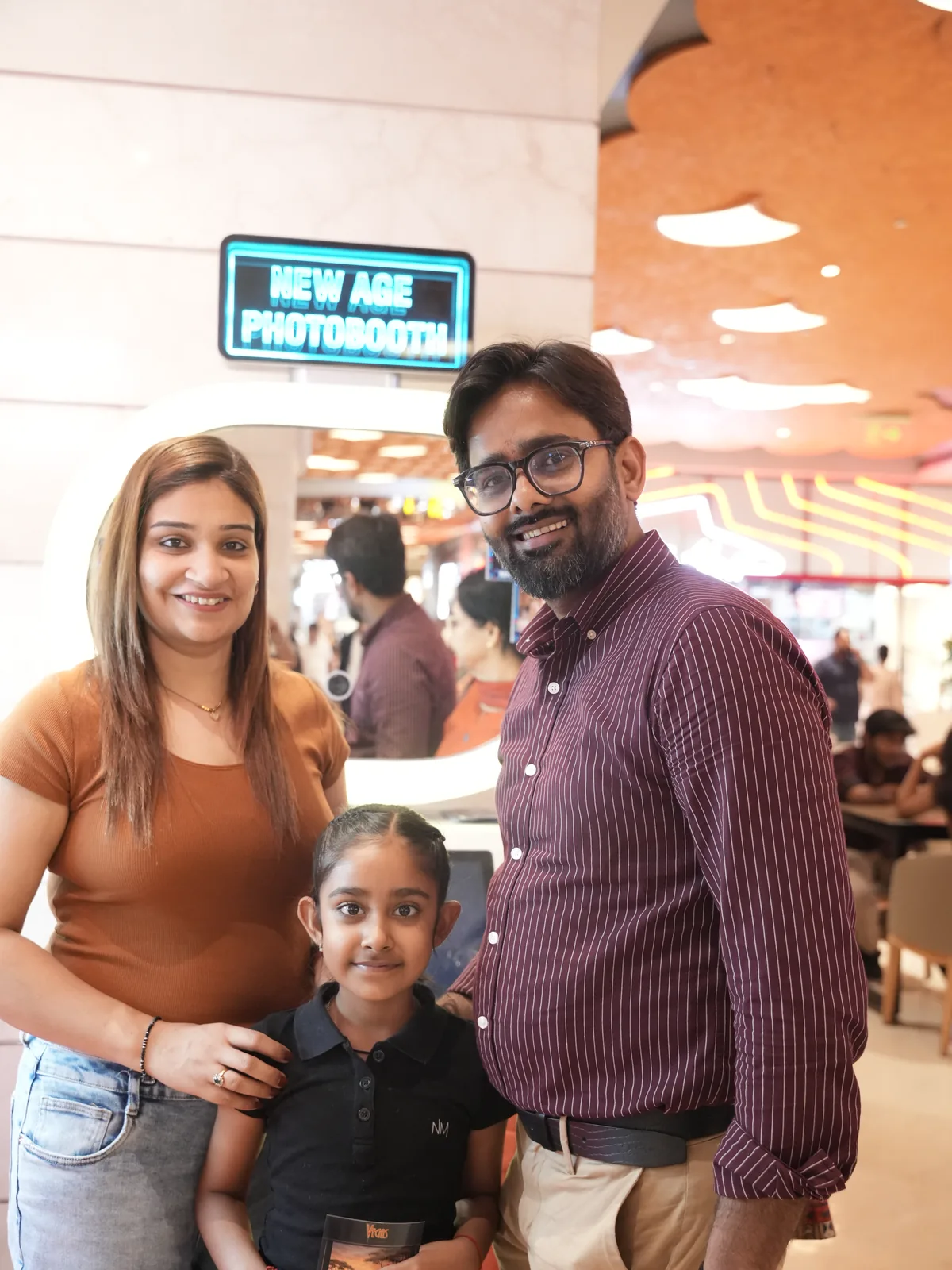 Couple and their daughter posing beside the Pikcha photo booth in Delhi