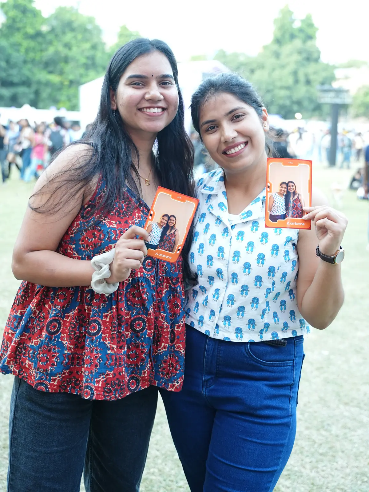 Two friends smiling with their photo booth prints at an IIT Delhi event