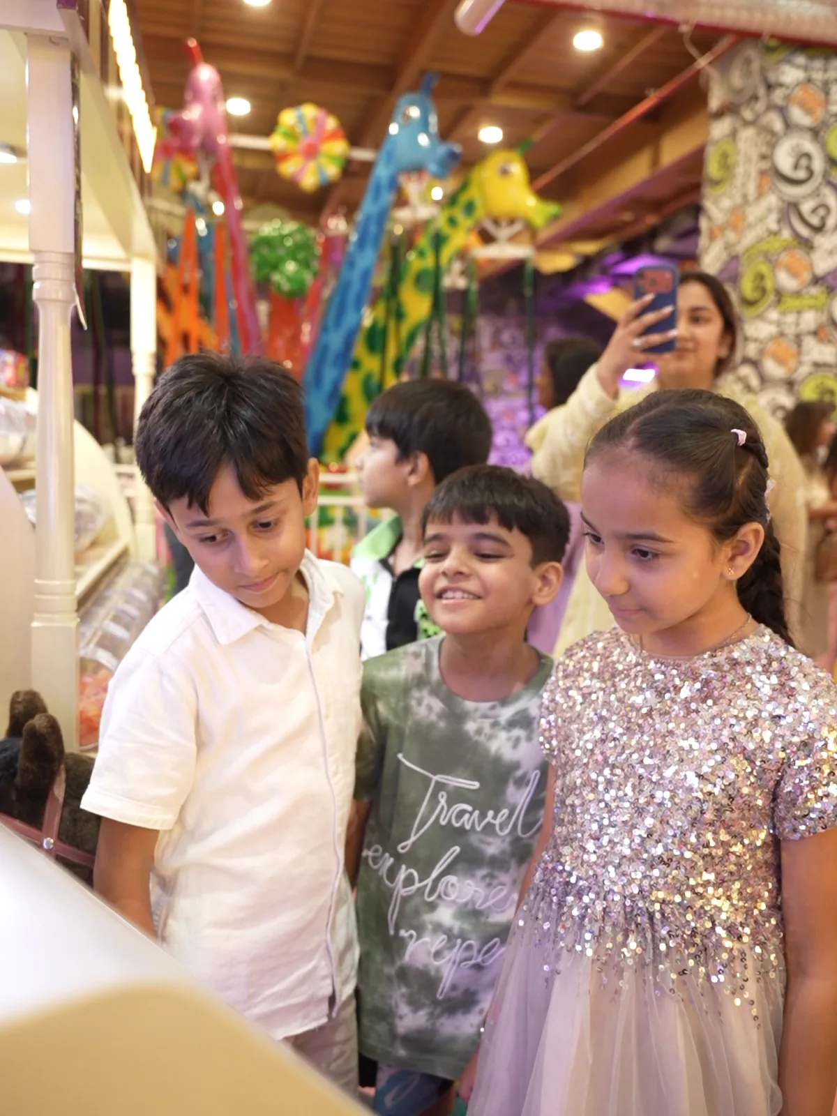 Three kids smiling together beside the Pikcha photo booth at Boombastic in Gurugram