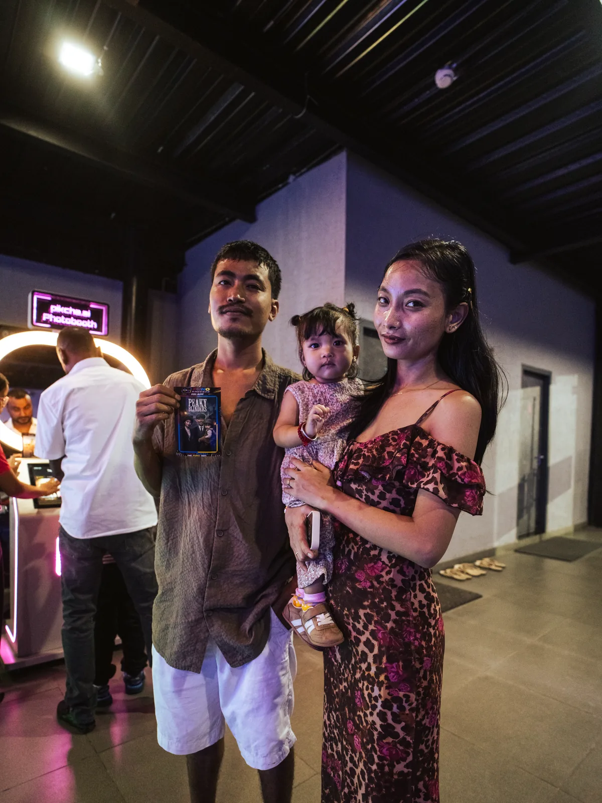 Couple with their baby holding the print from a Pikcha photo booth at an entertainment centre