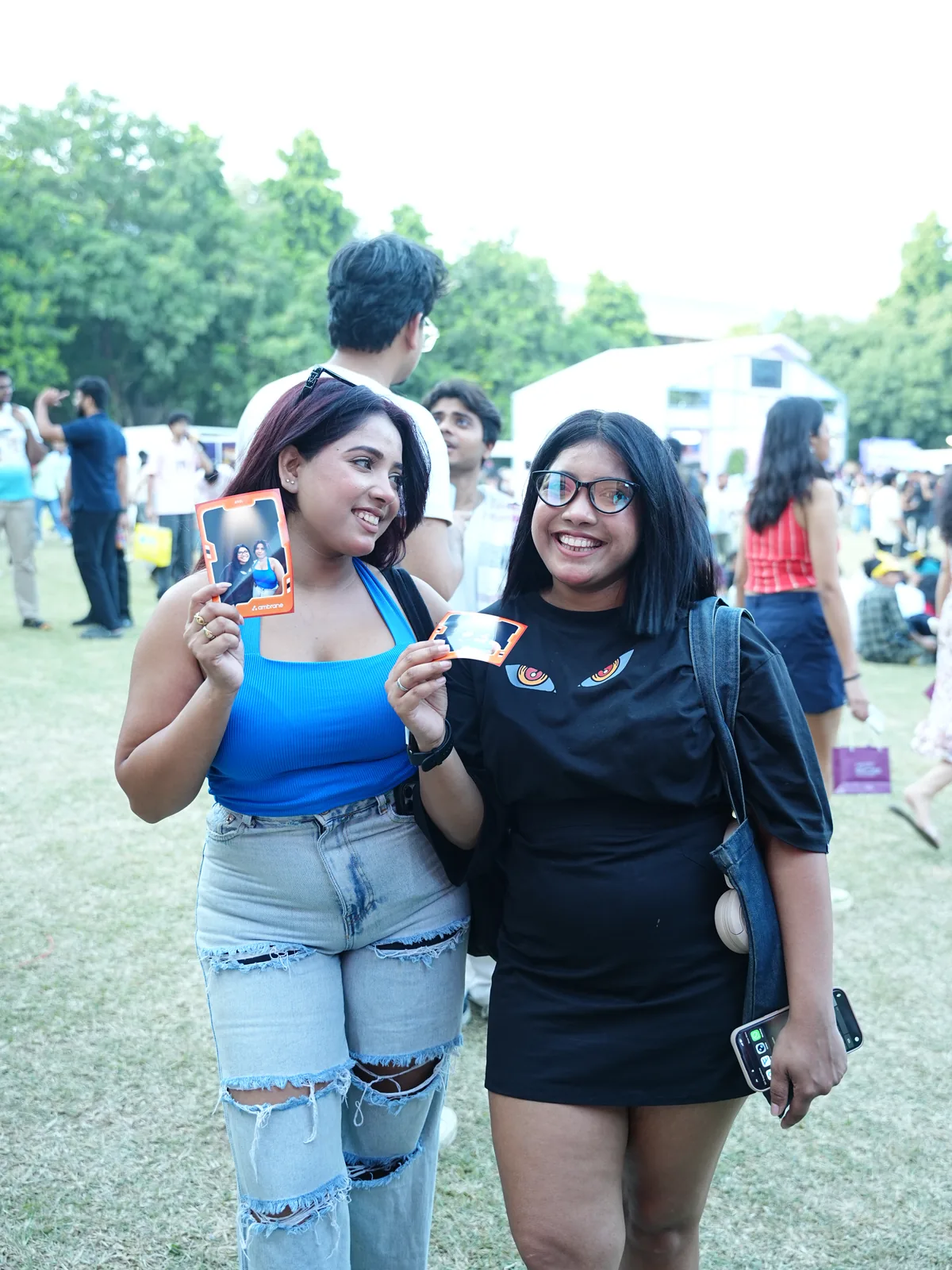 Two friends showing their orange framed photo booth prints at a college festival