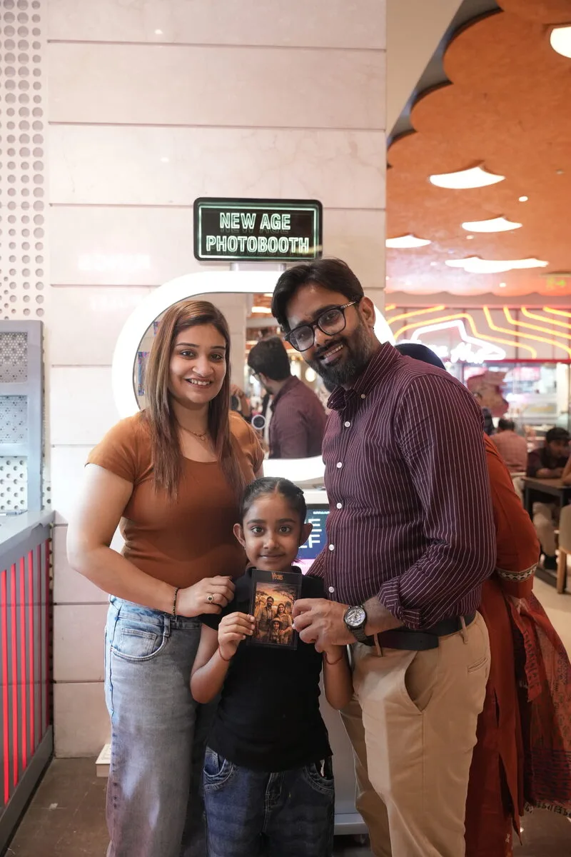 A family of three with their print at the Pikcha booth in a mall